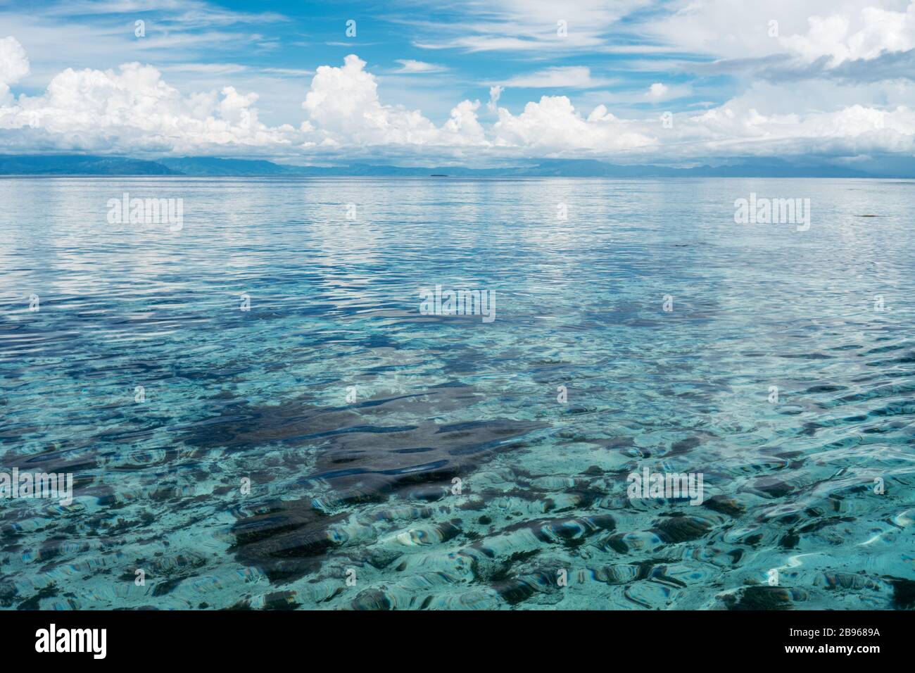 Türkisfarbenes Meerwasser mit blauem Himmel und cumulus-wolken in der Ferne. Stockfoto