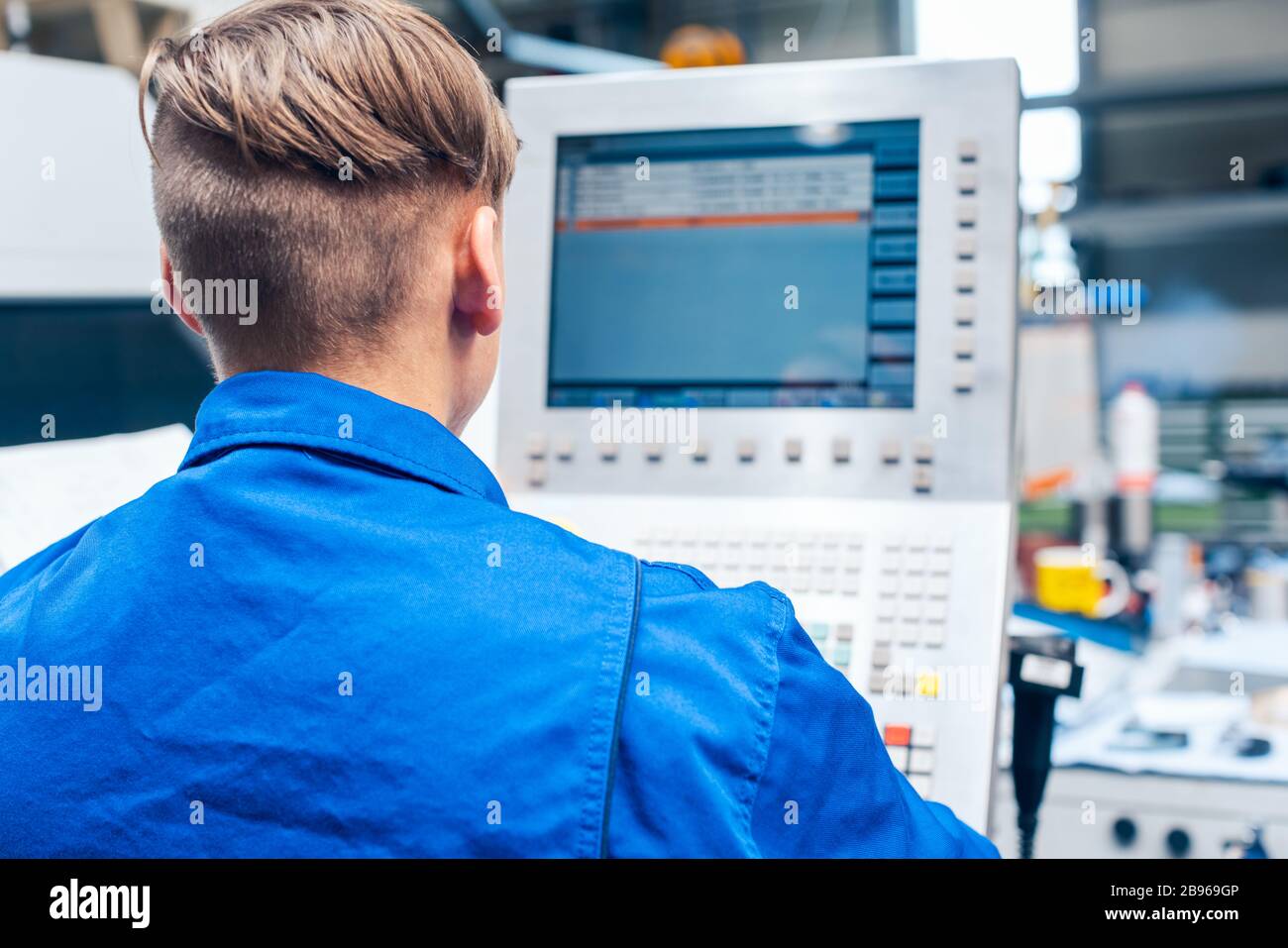 Junge Arbeiter programmieren Drehmaschine in der Fabrik Stockfoto