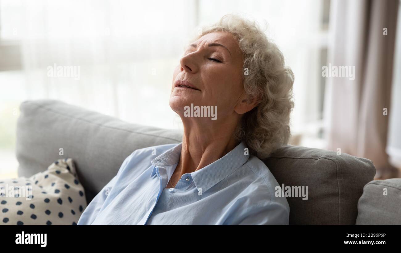 Reife Frau, die sich zu Hause auf der Couch entspannt Stockfoto