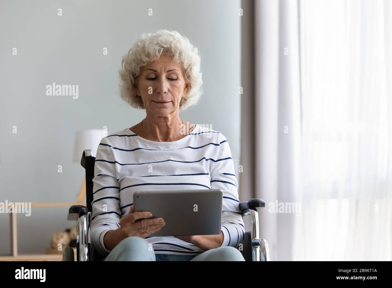 Smart Senior Disabled Woman beim Surfen im Internet auf dem Tablet Stockfoto