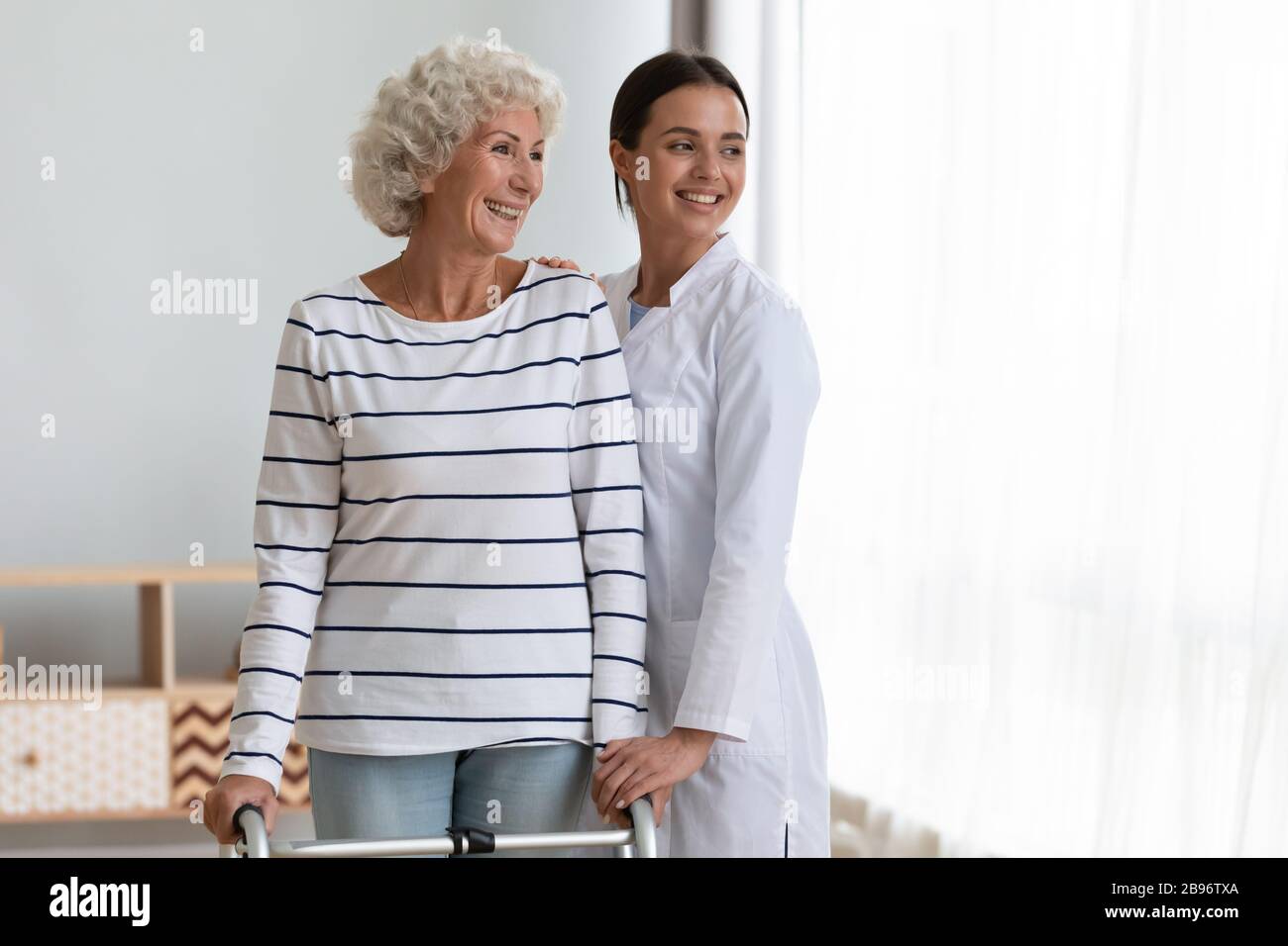 Lächelnde junge Krankenschwester und reife Patientin fühlen sich hoffnungsvoll für die Zukunft Stockfoto