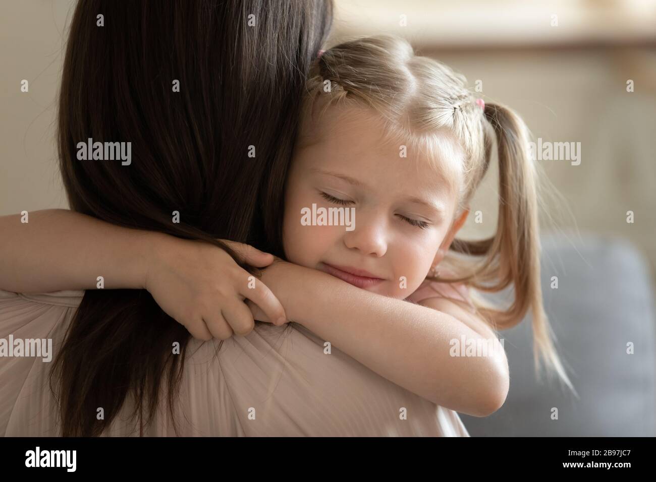 Liebevolles kleines Mädchen umarmen Mutter, die gemeinsam einen süßen Moment genießt Stockfoto