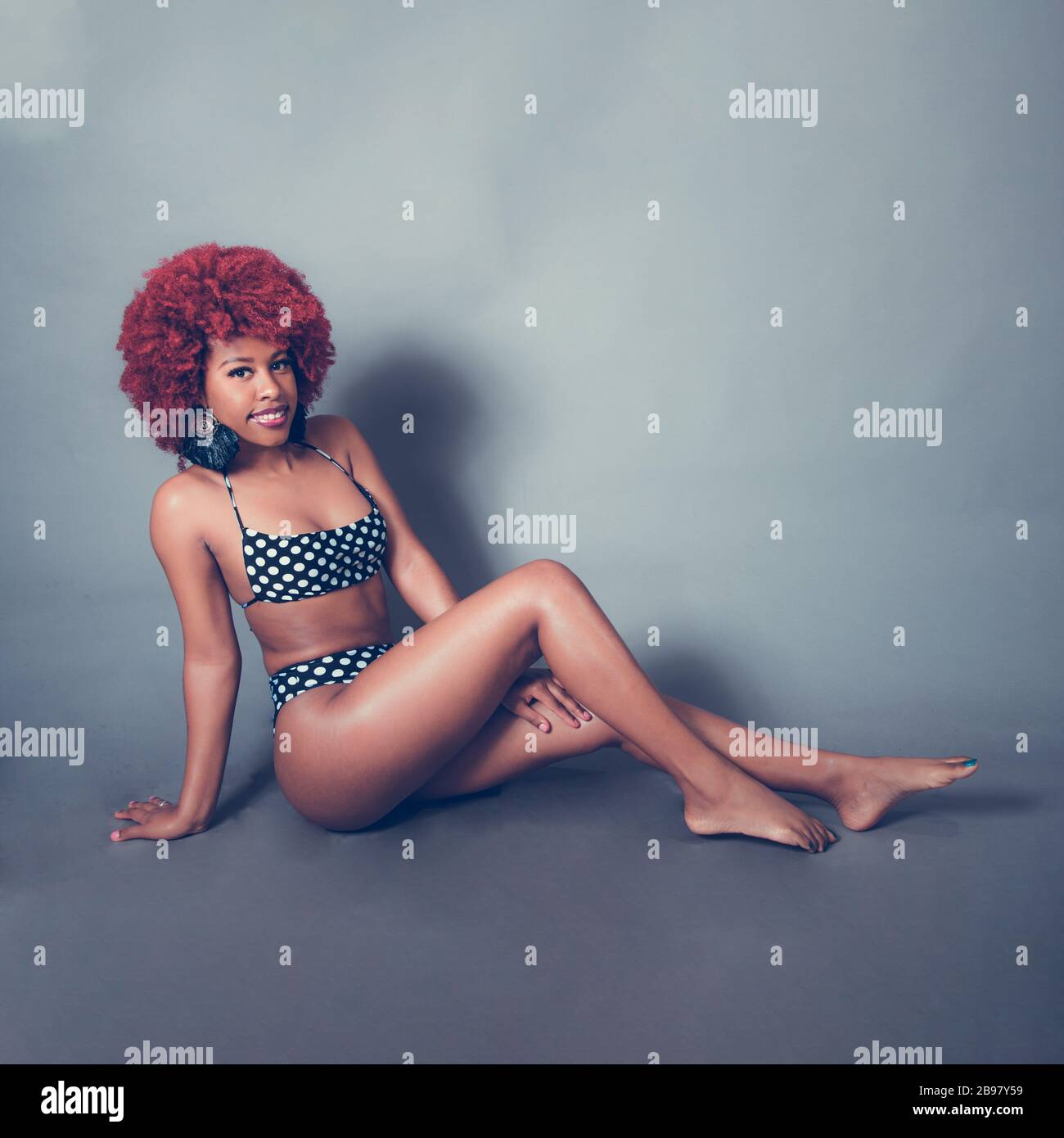 Karibisches schwarzes Mädchen mit rotem Afro im Badeanzug Stockfoto