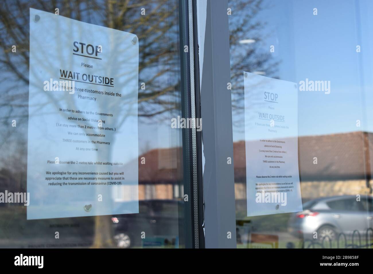 Hinweis in einem Apothekenfenster in Milton Keynes, in dem angegeben wird, dass maximal drei Personen aufgrund von Einschränkungen für Covid-19 zu einem beliebigen Zeitpunkt einreisen dürfen. Stockfoto