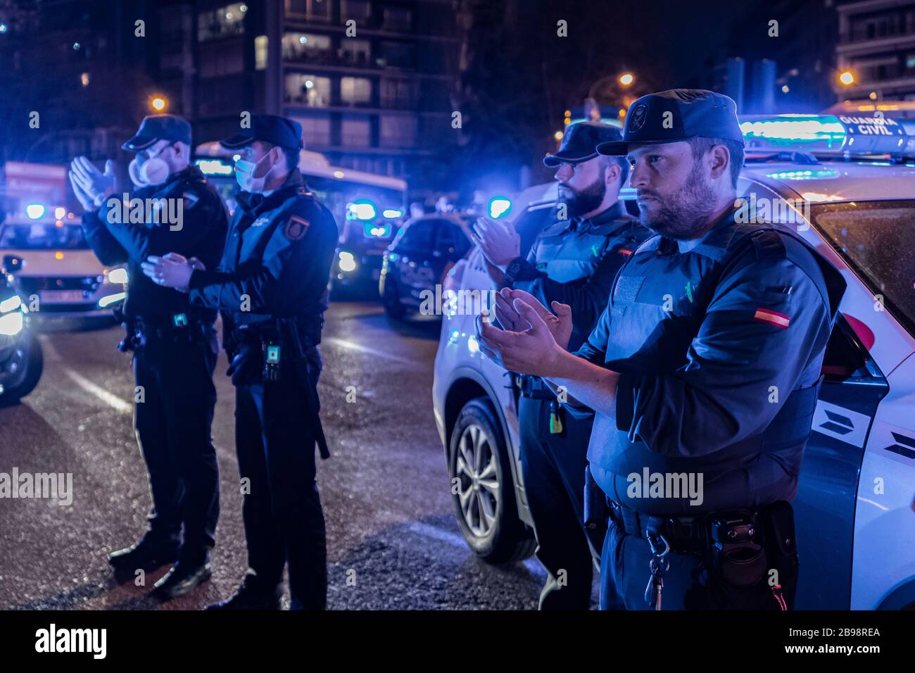 Zwei Polizisten der Nationalpolizei und zwei Beamte der Guardia Civil applaudieren, um ihren medizinischen Mitarbeitern zu zeigen, die gegen eine Pandemie mit Coronavirus kämpfen. Jeden Tag, um 20 Uhr, versammeln sich mehrere Polizeipatrouillen am Haupteingang des Krankenhauses Fundación Jiménez Díaz in der Innenstadt von Madrid. Polizeibeamte applaudieren, schalten ihre Autoscheinwerfer ein und ertönen ihre Sirenen für einige Minuten, um Ärzten und Krankenschwestern Tribut zu zollen, die gegen Coronavirus kämpfen Stockfoto