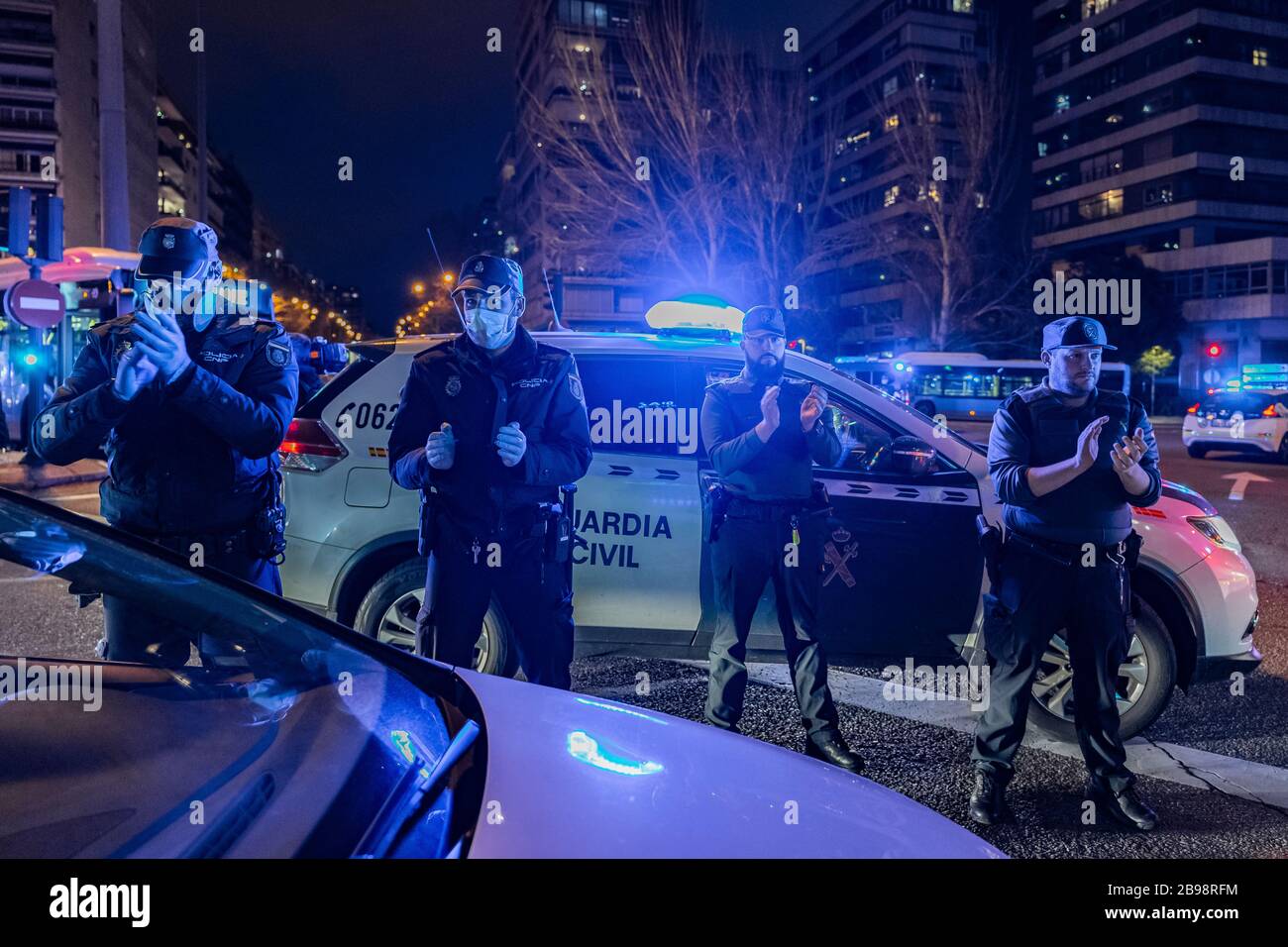 Zwei Polizisten der Nationalpolizei und zwei Beamte der Guardia Civil applaudieren, um ihren medizinischen Mitarbeitern zu zeigen, die gegen eine Pandemie mit Coronavirus kämpfen. Jeden Tag, um 20 Uhr, versammeln sich mehrere Polizeipatrouillen am Haupteingang des Krankenhauses Fundación Jiménez Díaz in der Innenstadt von Madrid. Polizeibeamte applaudieren, schalten ihre Autoscheinwerfer ein und ertönen ihre Sirenen für einige Minuten, um Ärzten und Krankenschwestern Tribut zu zollen, die gegen Coronavirus kämpfen Stockfoto