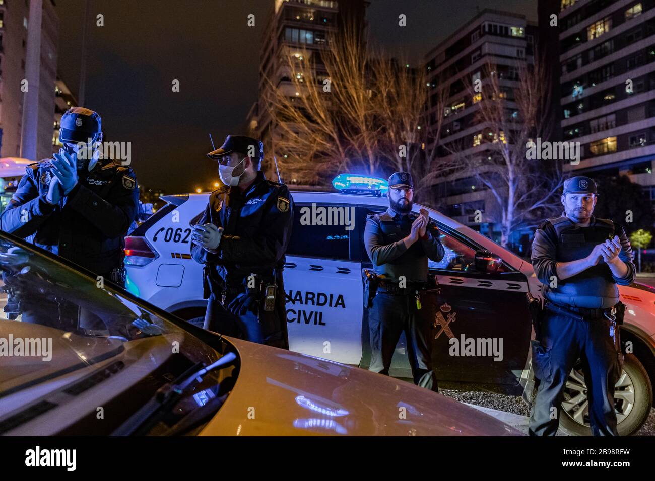 Zwei Polizisten der Nationalpolizei und zwei Beamte der Guardia Civil applaudieren, um ihren medizinischen Mitarbeitern zu zeigen, die gegen eine Pandemie mit Coronavirus kämpfen. Jeden Tag, um 20 Uhr, versammeln sich mehrere Polizeipatrouillen am Haupteingang des Krankenhauses Fundación Jiménez Díaz in der Innenstadt von Madrid. Polizeibeamte applaudieren, schalten ihre Autoscheinwerfer ein und ertönen ihre Sirenen für einige Minuten, um Ärzten und Krankenschwestern Tribut zu zollen, die gegen Coronavirus kämpfen Stockfoto