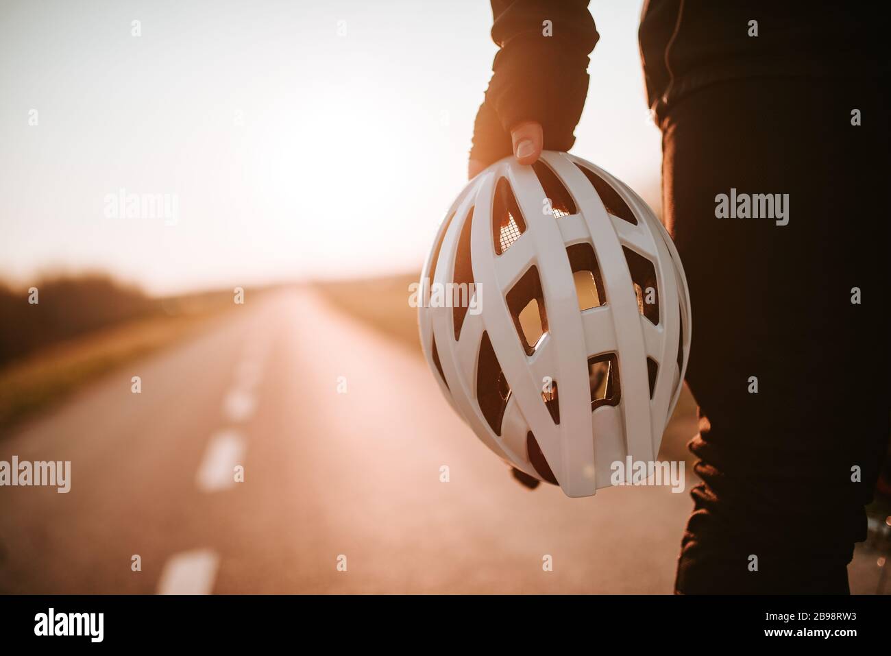 Der Radfahrer hält den Helm in der Hand und steht auf der Straße Stockfoto