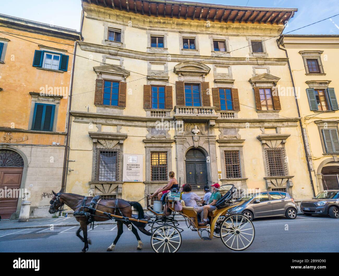 Eine Pferdekutsche mit Besichtigungstouristen führt an der Pisa Akademie der schönen Künste in der Via Santa Maria, Pisa, Toskana, Italien vorbei Stockfoto