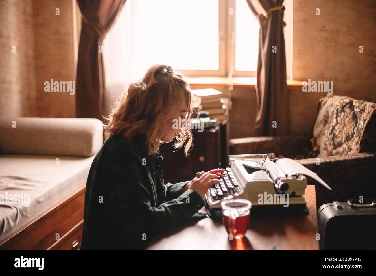 Junge weibliche Schriftstellerin, die zu Hause Schreibmaschine verwendet Stockfoto