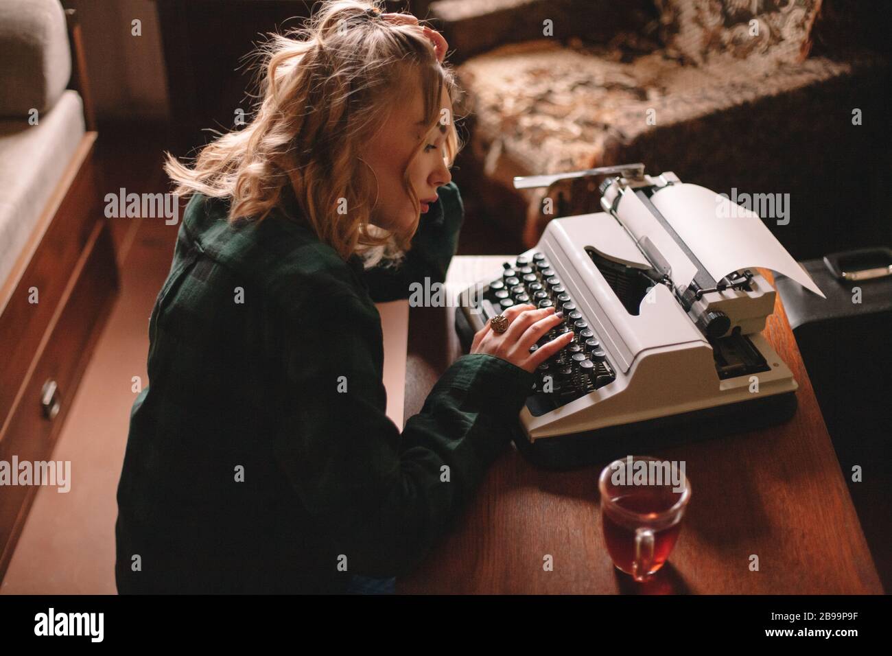 Junge weibliche Schriftstellerin, die zu Hause Schreibmaschine verwendet Stockfoto