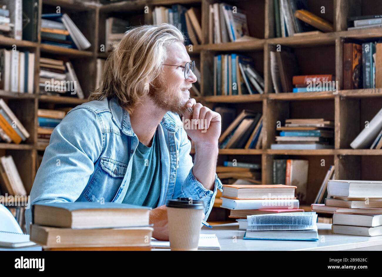 Nachdenklicher junger Student mit Kinn auf der Hand schaut weg. Stockfoto