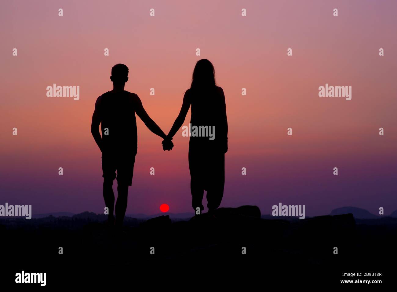 Eine Silhouette eines Paares, das die Hände bei Sonnenuntergang hält. Stockfoto