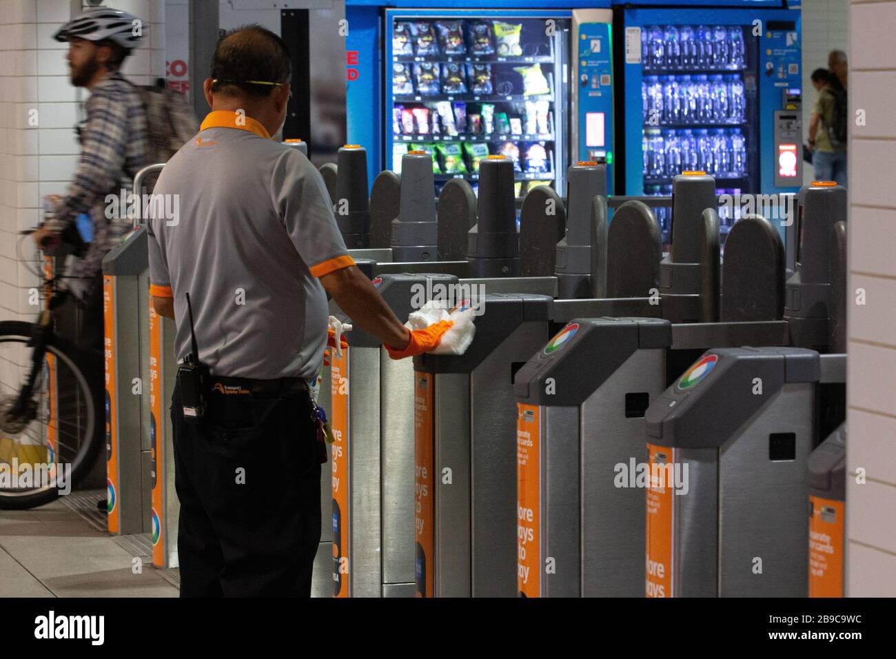 SYDNEY, AUSTRALIEN, 24. März 2020, wird ein Mitarbeiter des Bahnhofs beobachtet, wie er die Oberfläche von Fahrkartensperren am Rathausbahnhof von Sydney nach der Reaktion der Regierung auf den Ausbruch des Coronavirus saniert, um nicht essentielle Geschäfte zu schließen und den physischen Kontakt zwischen Menschen zu begrenzen. Credit: Sebastian Reategui/Alamy Live News Stockfoto