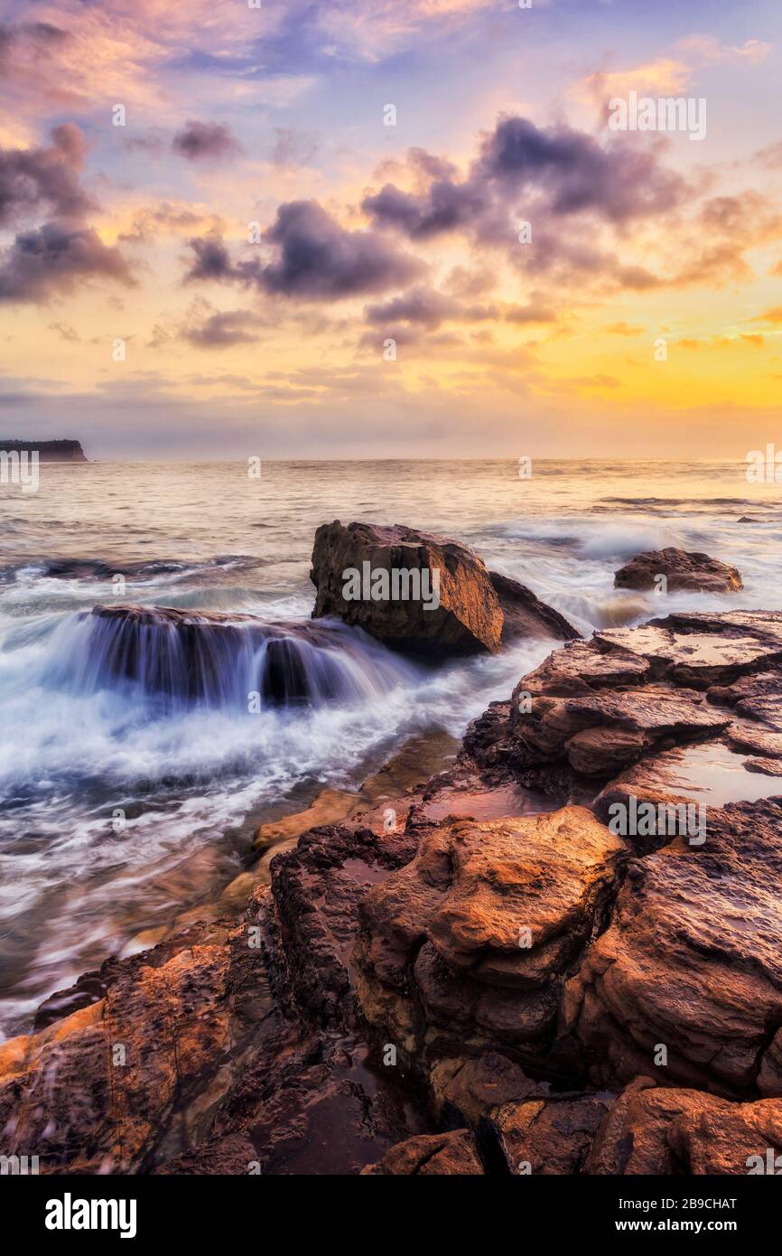 Gelbe Sandsteinfelsen an den Nordstränden von Sydney rund um Turimetta machen sich bei Sonnenaufgang auf den Kopf. Stockfoto