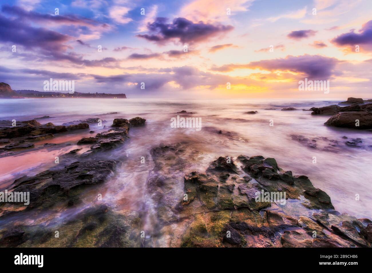 Grüne Algen auf Sandsteinfelsen rund um Turimetta entlang der Nordstrände von Sydney bei Sonnenaufgang. Stockfoto