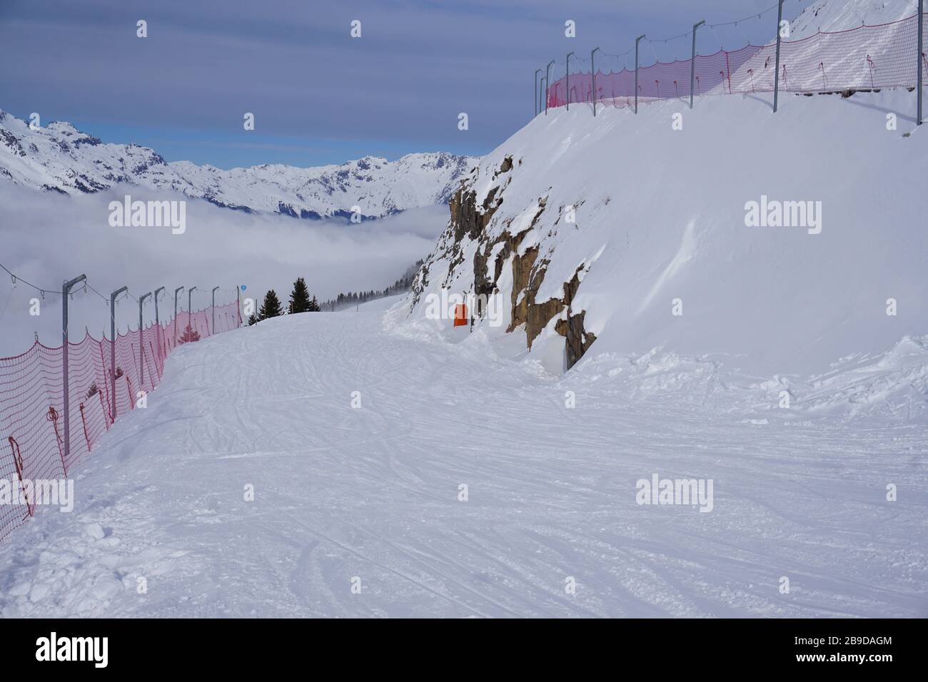 Haarnadel am Hang des Skigebiets Alpe d'Huez, Frankreich, mit rotem Netzschutz für Niederschläge Stockfoto