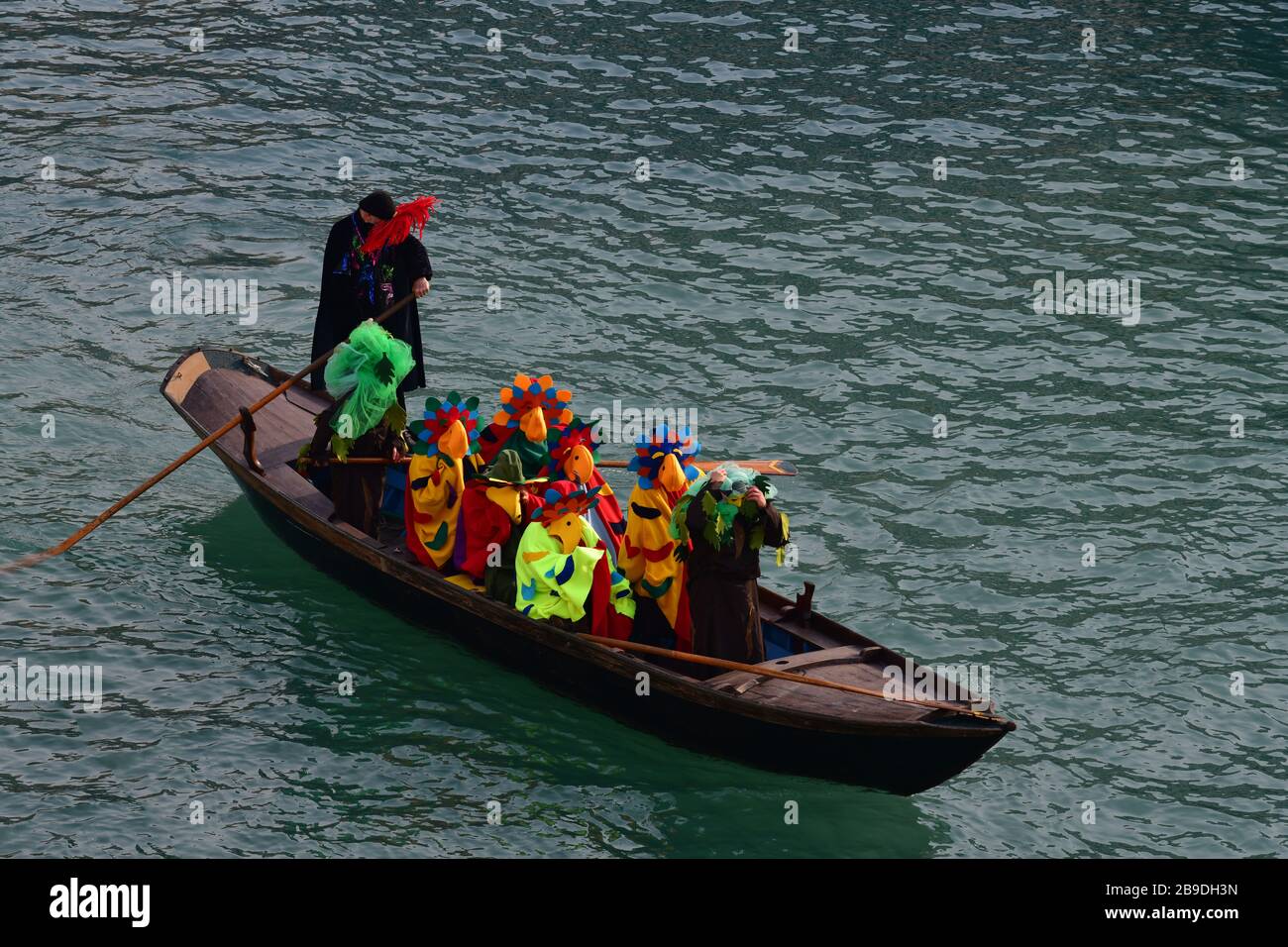 Eine einzige Gondel voller Menschen, die während des Karnevals in Venedig als Papageien in bunten Kostümen verkleidet waren Stockfoto