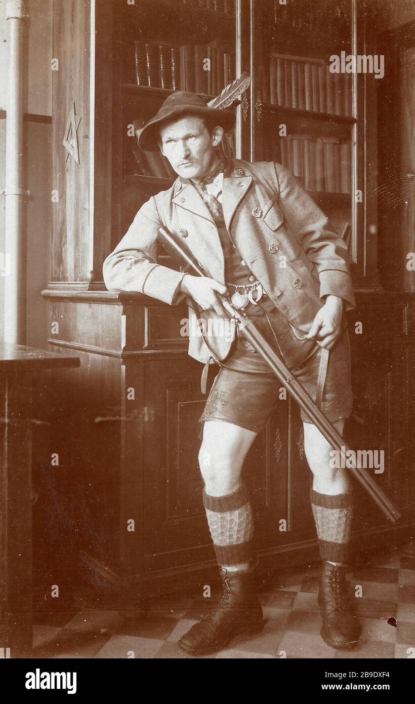 Ein Jäger mit kurzer Lederhose, Charivaria und doppeltem Gewehr im Anschlag  posiert für ein Foto. Unbekannter Ort, 1925. [Automatisierte Übersetzung]  Stockfotografie - Alamy