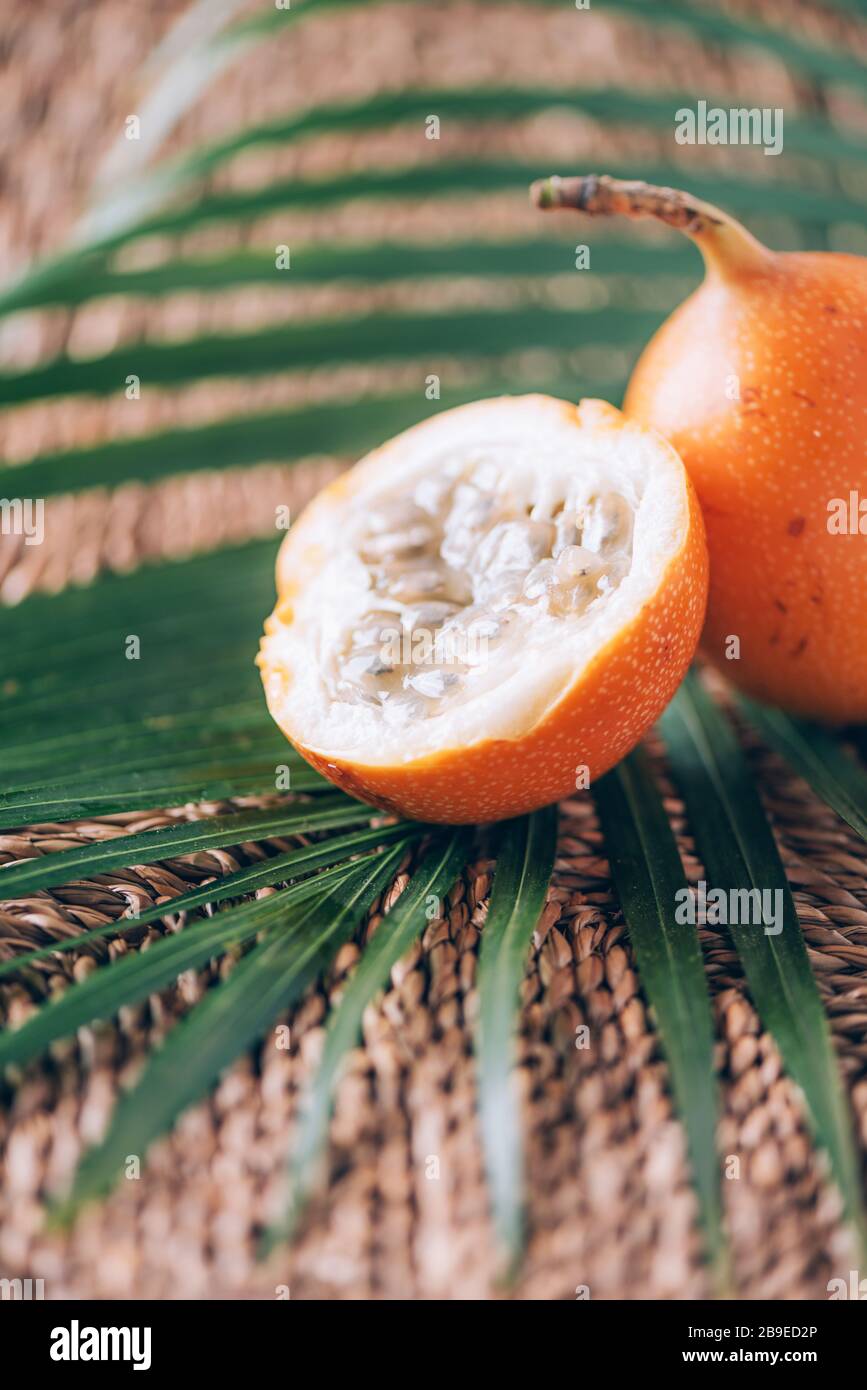 Süße Granadilla oder Granadia mit Palmblättern auf Rattanhintergrund. Kopierbereich. Banner für kreatives Design. Sommerzeit. Exotische Küche, tropische Obstkonce Stockfoto