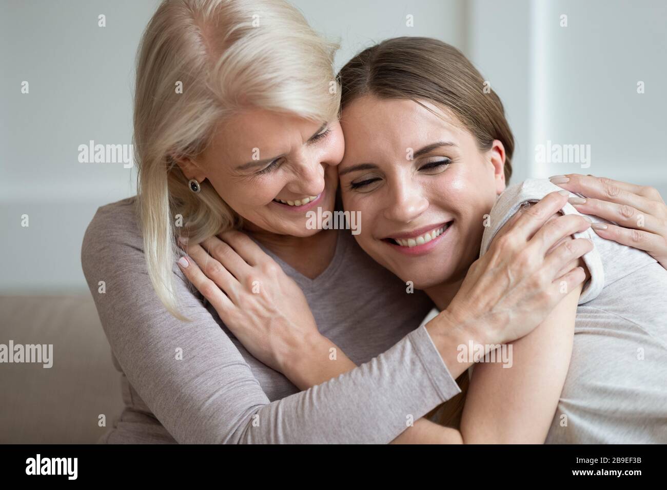 Glücklich lächelnde ältere Mutter und Erwachsene Tochter umarmen und lachen Stockfoto