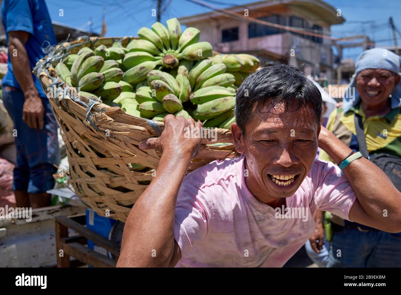 Nahporträt eines Portiers, der einen schweren Bananenkorb trägt. Stockfoto