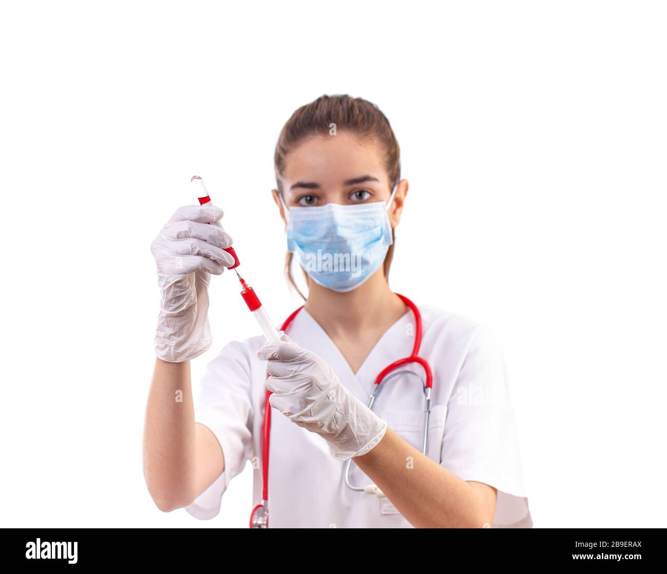 Junge Frau Doktor in weiße Uniform, maske und handschuhe mit Spritze Stockfoto