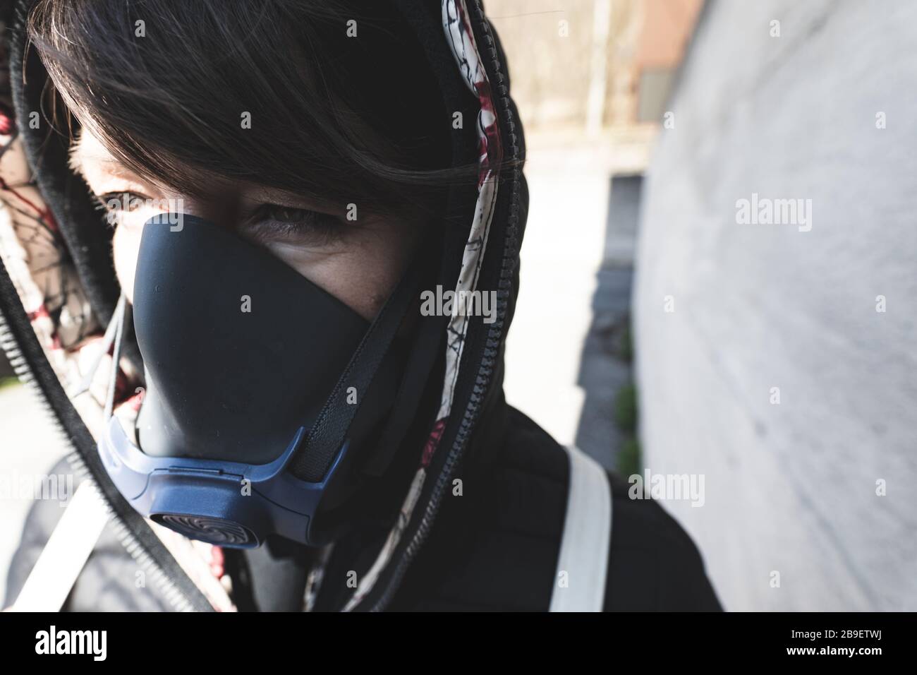 Frau mit einer Gasmaske, die auf den Straßen der Stadt spaziert und dabei eine Corona-Virus-Pandemie oder eine postatomare Welt überlebt Stockfoto