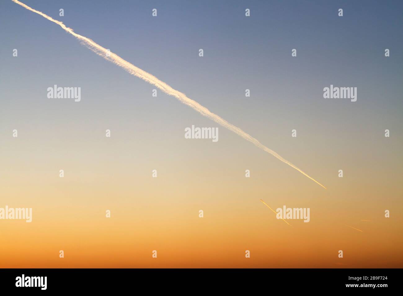 Kondensstreifen am Himmel bei Sonnenuntergang oder Sonnenaufgang Stockfoto