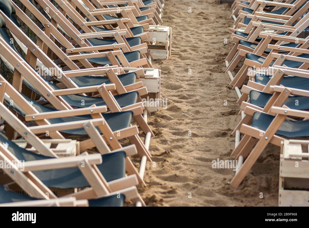 Zwei gegensätzliche Reihen von schwebenden leeren Liegen in Reihen reihten sich in Ordnung am Strand im Sand, zwei gegenüberliegende Reihen von aufgerichteten l Stockfoto