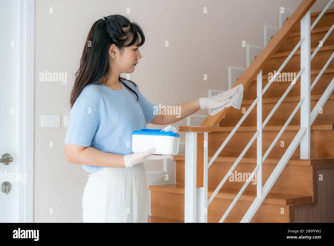 Asian Woman desinfiziert den Treppenhausbehälter mit desinfizierenden Einwegtüchern aus dem Karton. Verhindern Sie Virus und Bakterien, verhindern Sie Kovid19, Corona Stockfoto