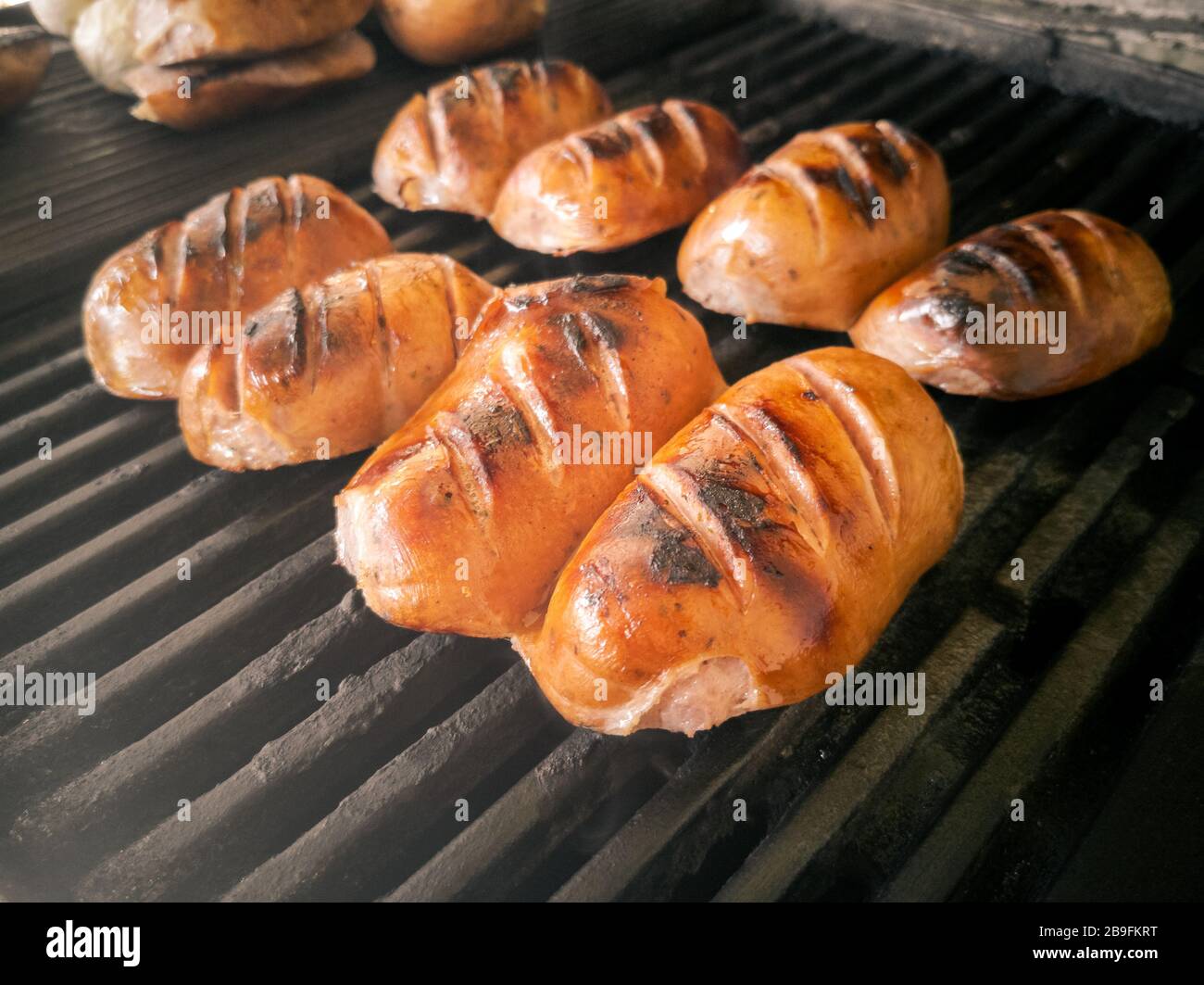 Vier mürrische traditionelle bayrische Knackwurst aus Regensburg schneiden halbgeröstet auf gusseisernem Grillrost Stockfoto