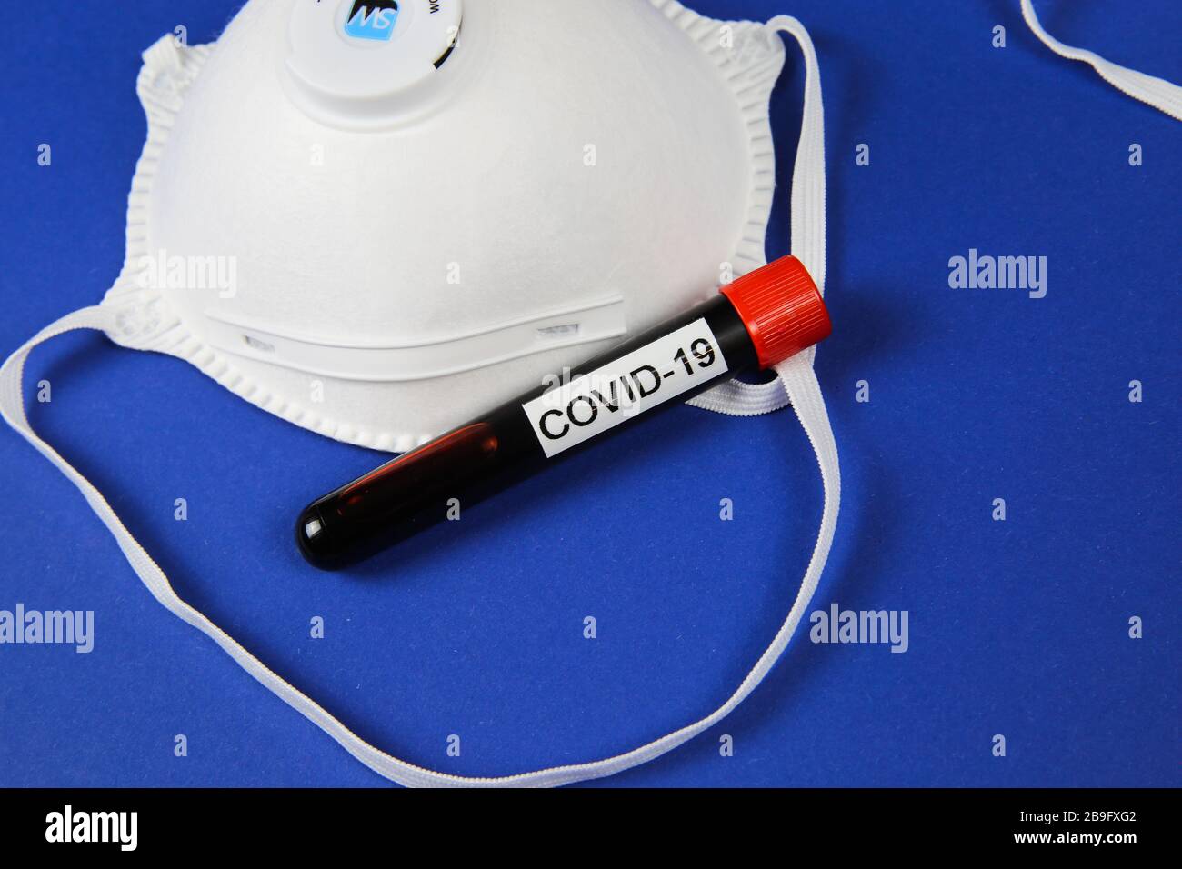 Viersen, Deutschland - 22. März. 2020: Nahaufnahme der gesichtsschutzmaske ffp2 mit Durchstechflasche mit Blutprobe Stockfoto