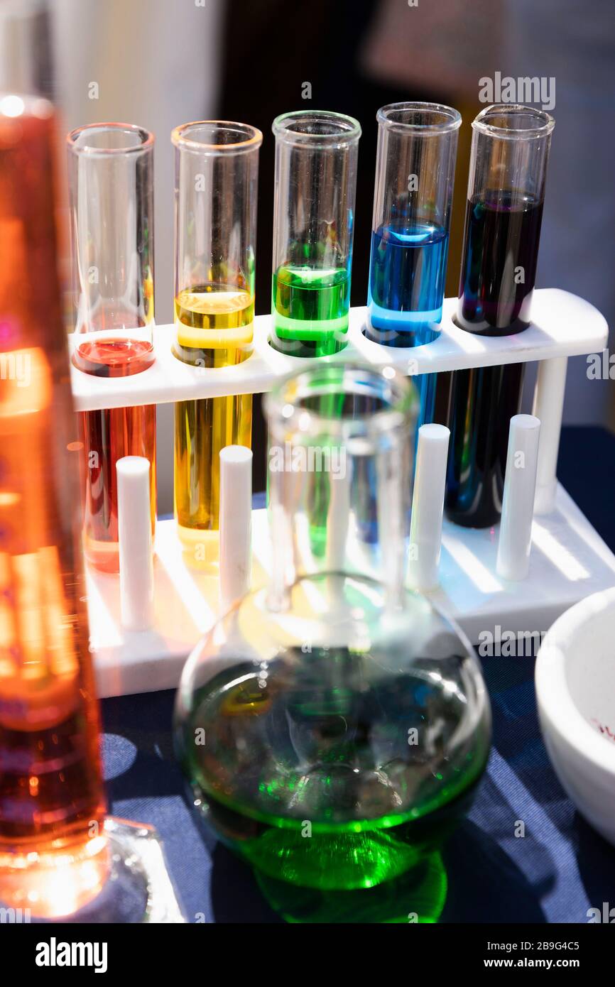 Mehrfarbige Flüssigkeit im Reagenzglasgestell und Becher Stockfoto