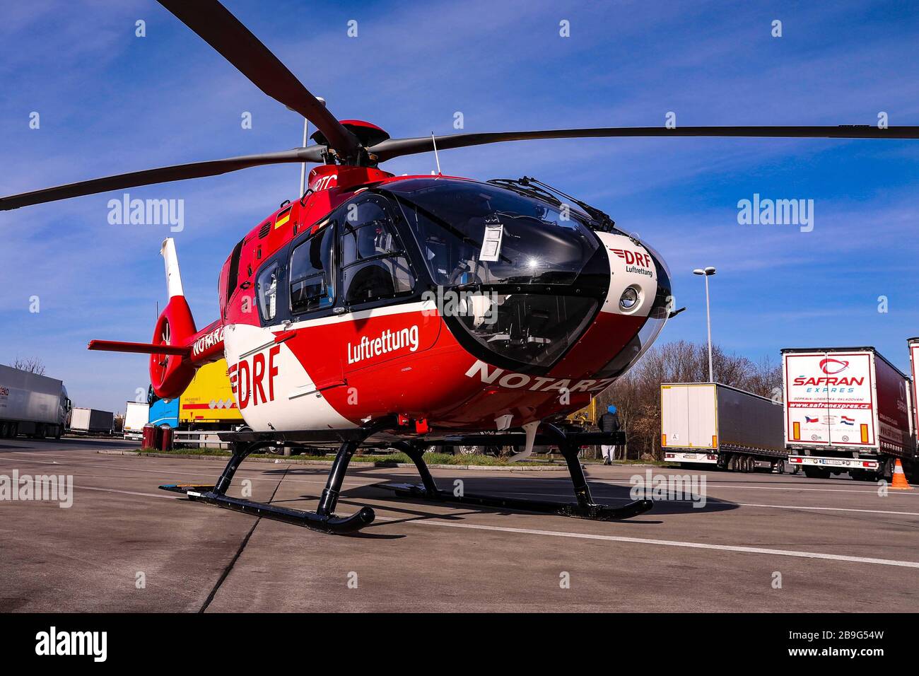 17. März 2020, Sachsen, Dresden: Im Vordergrund steht ein Rettungshubschrauber der DRF mit der Aufschrift "Notarzt". Im Hintergrund des Bildes stehen zahlreiche Lastwagen Foto: Tino Plunert / dpa-Zentralbild / ZB Stockfoto