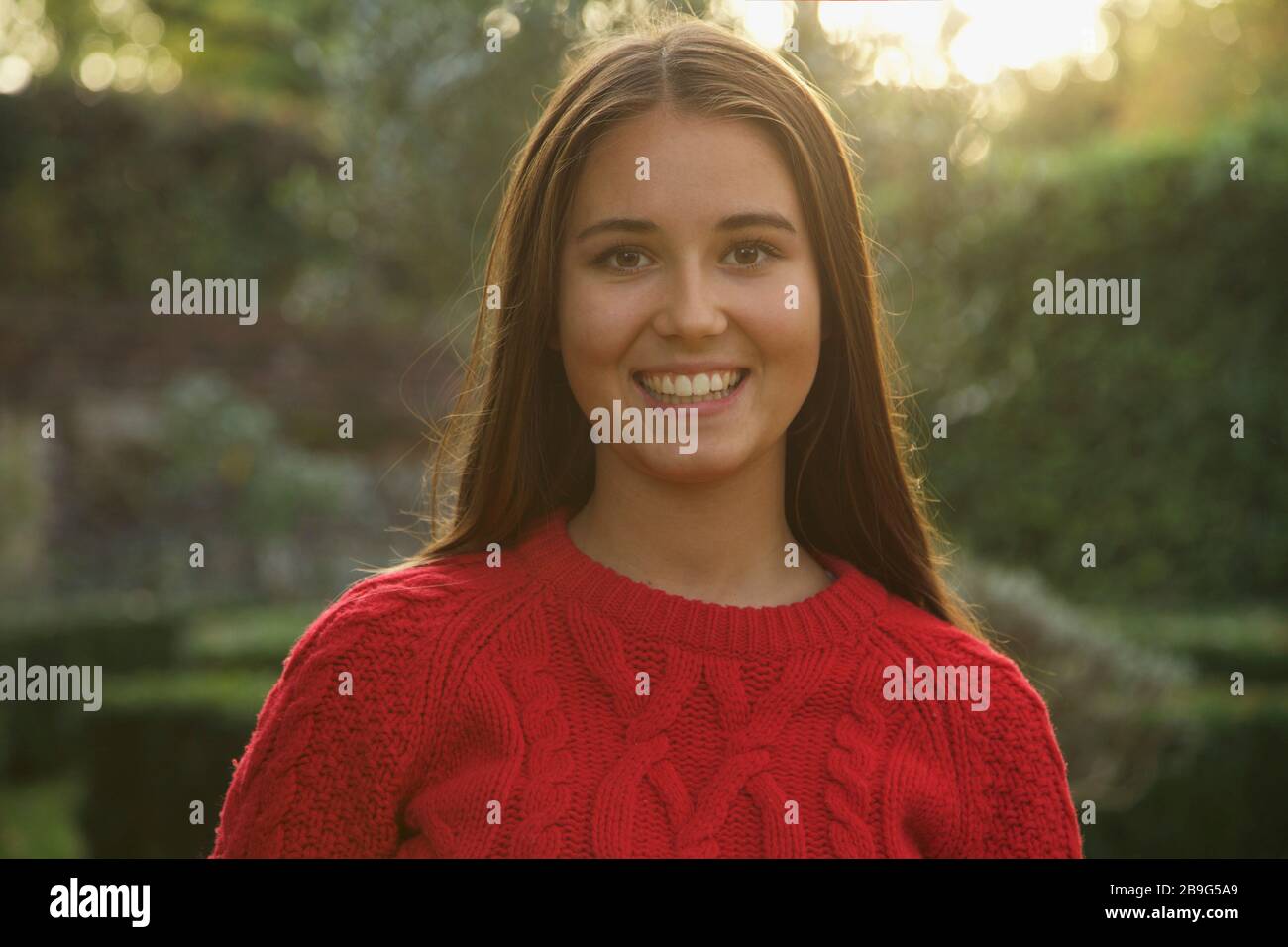 Portrait fröhliches Mädchen im Teenager-Alter im roten Pullover im Park Stockfoto