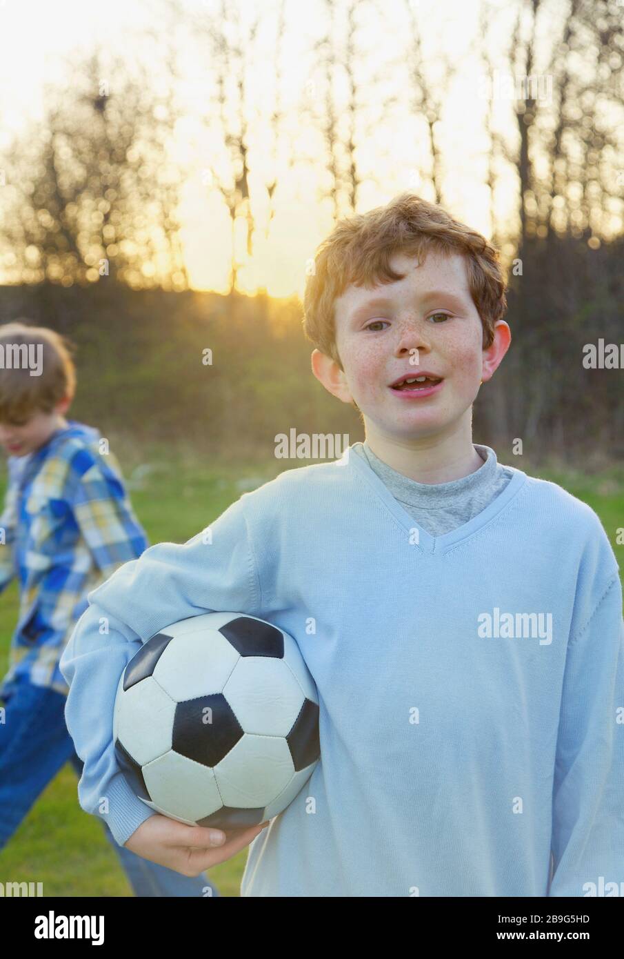 Portraitjunge mit Freckles, die Fußballball im Park halten Stockfoto