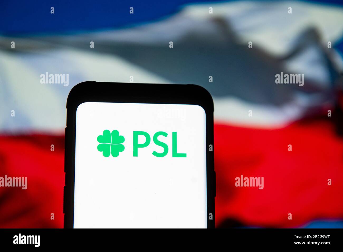 In dieser Abbildung wird ein PSL Polskie Stronnictwo Ludowe Logo auf einem Smartphone angezeigt.die polnische Nationalflaggen wird als Hintergrund angezeigt. Stockfoto