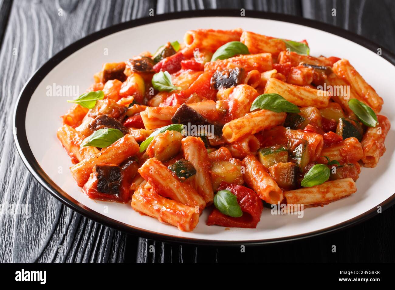 Tortiglioni Pasta Diät-Rezept mit Sommergemüse und in Tomatensauce in einer Platte auf dem Tisch backen. Horizontal Stockfoto