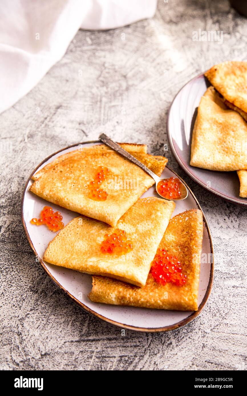 Traditionelle russische Pfannkuchen mit rotem Kaviar. Gebratene Crepes mit Kaviar und saurer Sahne Stockfoto