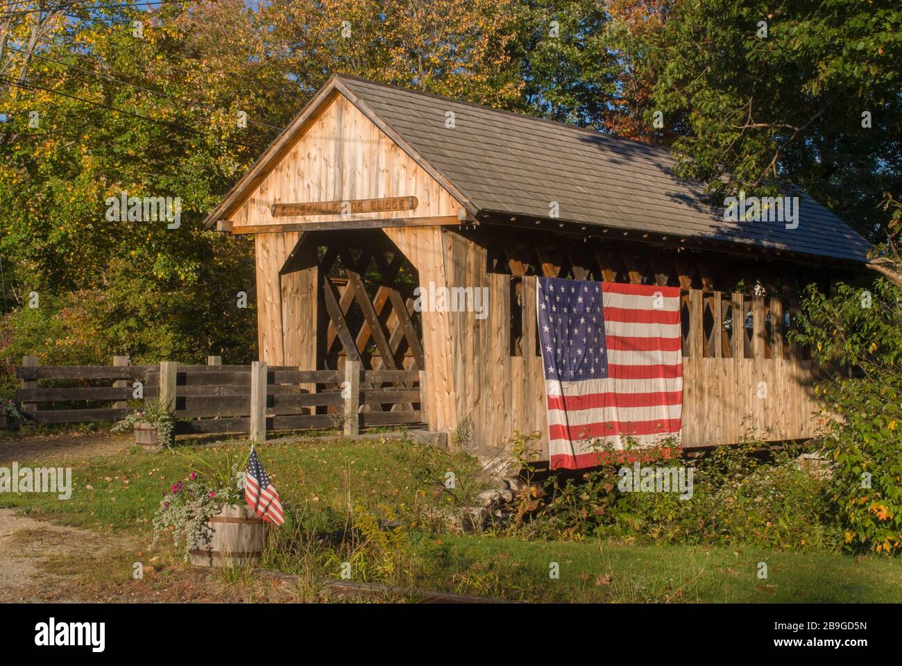 Die Brücke Cilleyville bog covered Bridge, die im Jahre 1887 im Lattice Truss Stil der Stadt erbaut wurde, überspannt Pleasant Brook in Andover, NH. Es ist mit einem großen Ameri drapiert Stockfoto