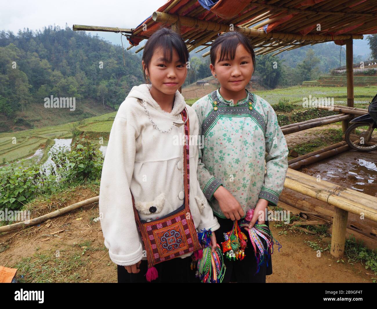 Zwei junge Mädchen, die Armbänder an Touristen verkaufen, die in Sapa, Vietnam wandern Stockfoto