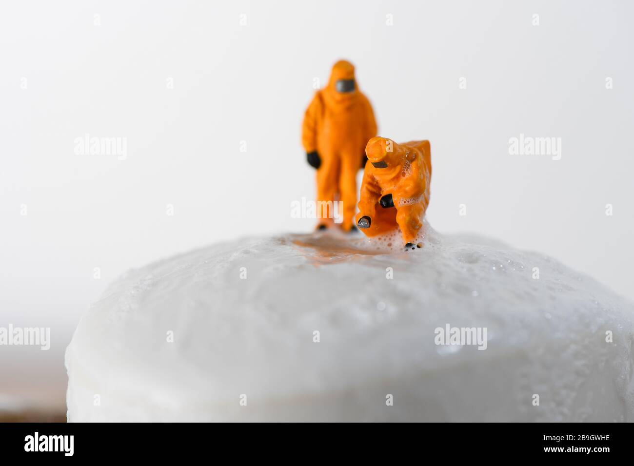 Konzeptbild für Coronavirus mit Miniaturmenschen auf einer Seifenleiste in Haselmatt-Anzügen, die auf Bakterien getestet werden. Stockfoto