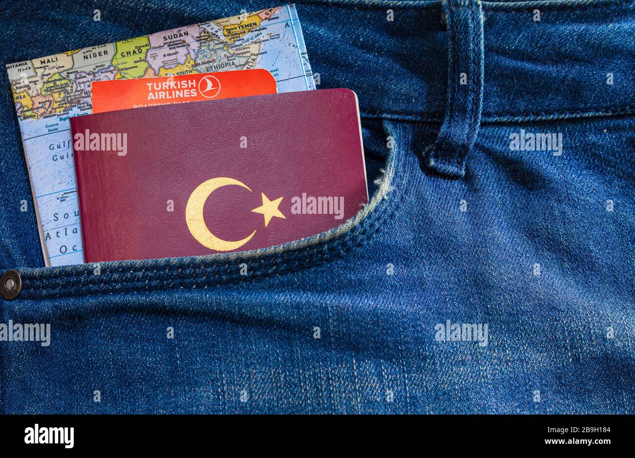 Ein türkischer Pass, ein Turkish Airlines Ticket und eine Weltkarte in einer Tasche mit blauer Jeans. Stockfoto