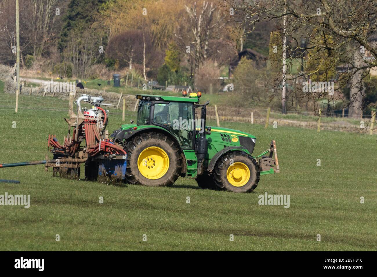 Ein Bauer treibt einen Traktor an, der Gülle über ein Feld verteilt. Stockfoto