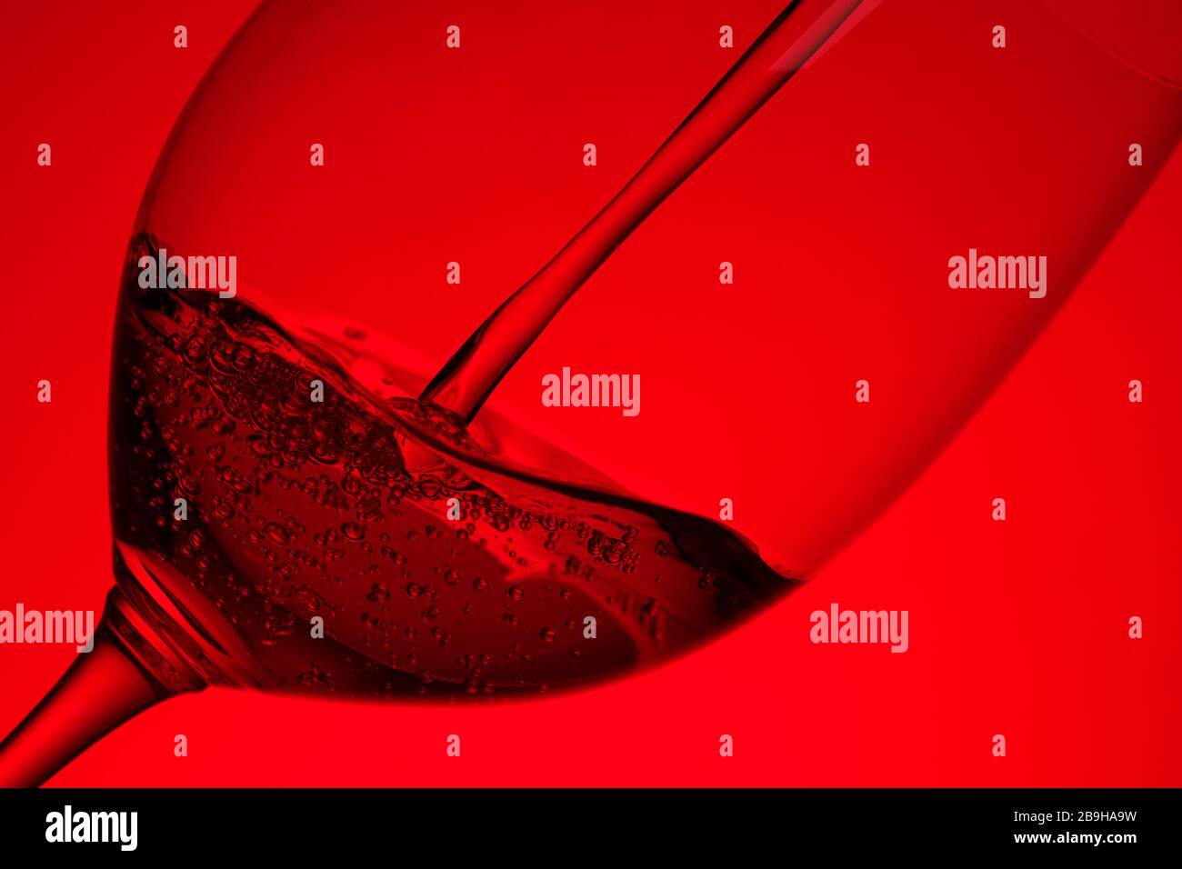 Rotwein, der in einem bordeaux Glas in Hintergrundbeleuchtung gießt Stockfoto