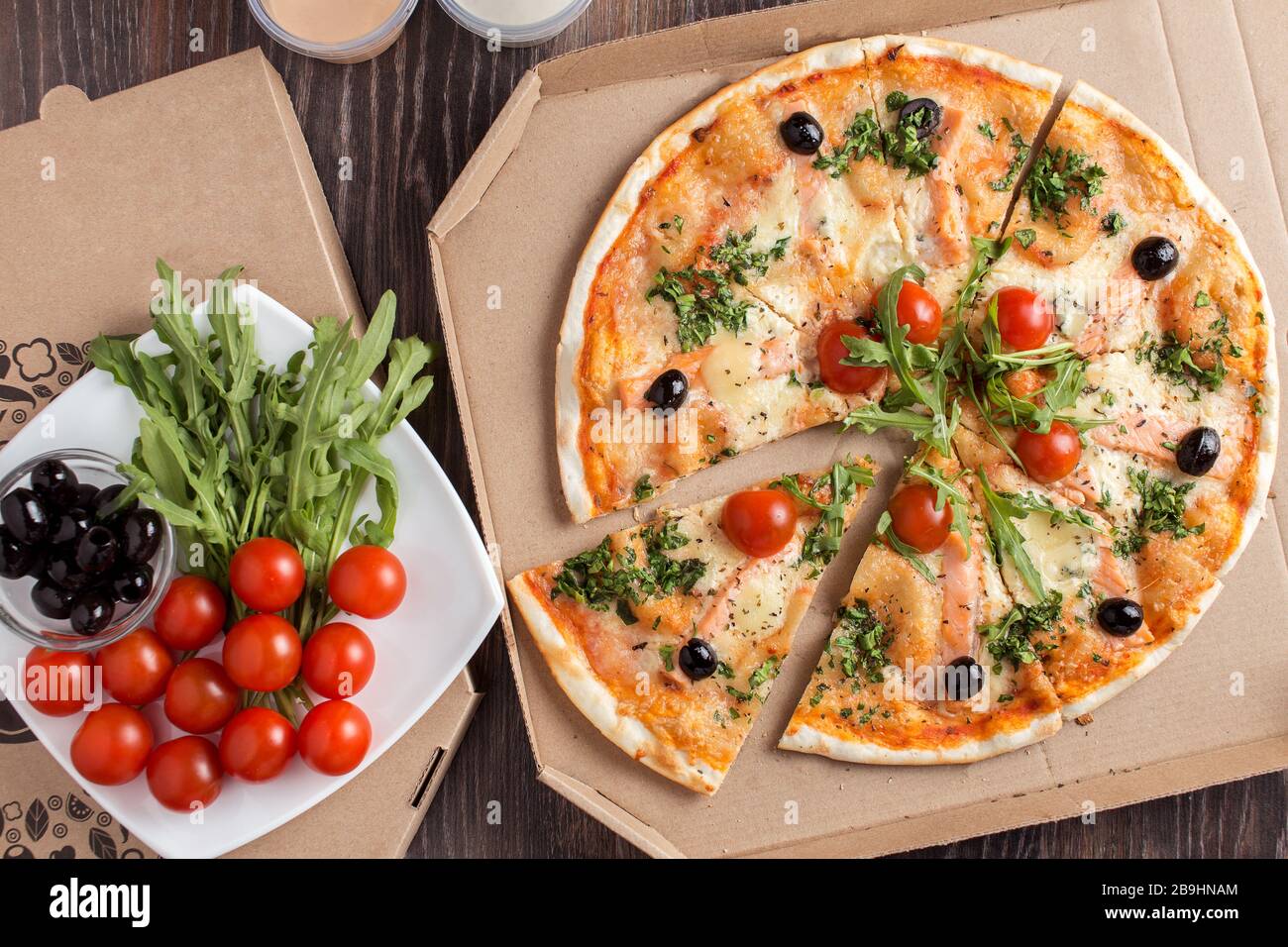 Pizza mit dünner Kruste und Lachs in Kartonverpackung Stockfoto