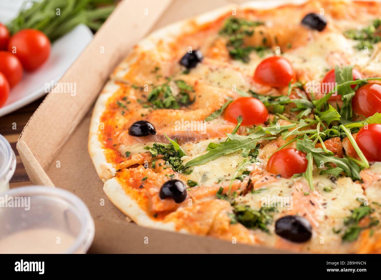Italienische Pizza mit dünner Kruste und Lachs im Karton Stockfoto