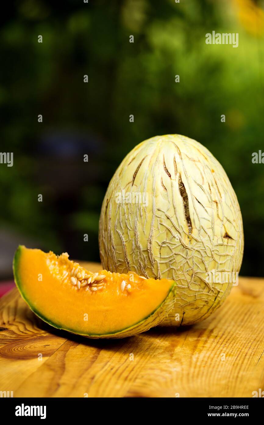 Reifes süßes, geschnittenes Erbstück Melone auf rustikalem Holz in einem Garten Stockfoto