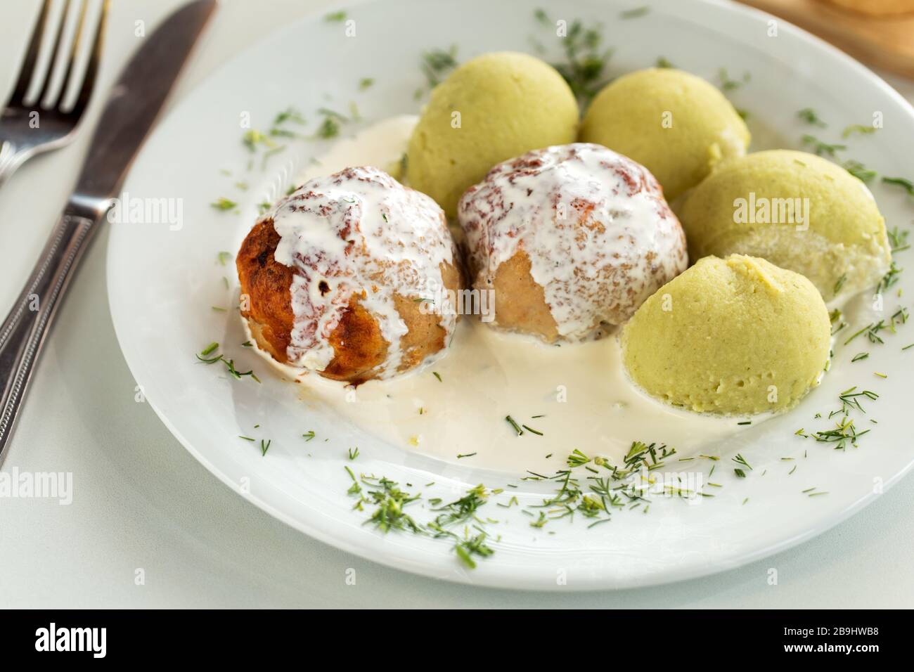 Gebratene Fleischbällchen aus Schweinefleisch mit Sahnesauce und Kartoffelpüree mit Spinat Stockfoto